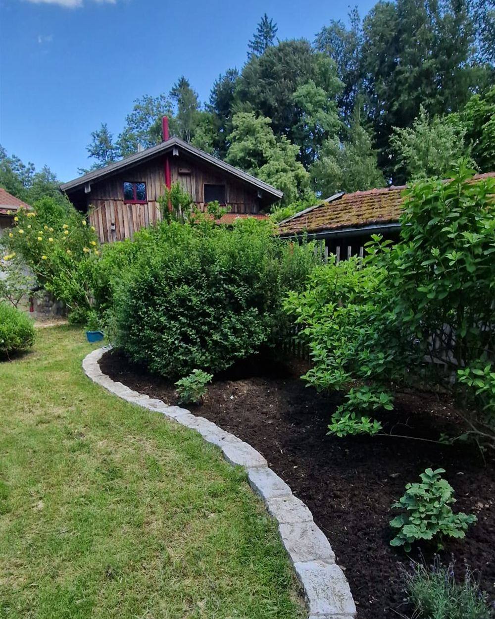 Naturnah gestalteter Garten mit geschwungener Natursteinkante zwischen Rasen und Staudenbeet