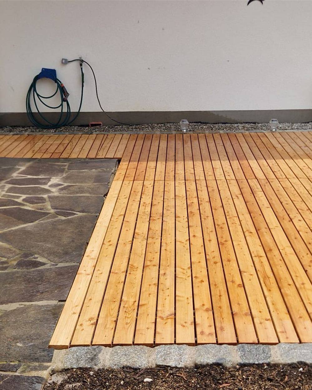 Neu verlegte Holzterrasse mit angrenzendem Natursteinpflaster und Granitkante